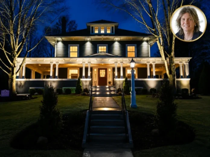 John Rzeznik house featuring an elegant luxury home exterior at night with illuminated windows, a large covered porch, landscaped grounds,