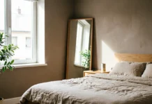 11 Bedroom Mirror Ideas That Make Your Room Look Bigger & Brighter Bedroom mirror ideas with a full-length mirror reflecting natural light in a small bedroom