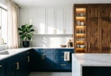 11 Gorgeous Kitchen Cabinet Designs to Elevate Your Kitchen in 2026 Modern kitchen cabinet designs featuring navy blue shaker base cabinets, white upper cabinets, walnut wood pantry cabinets, brass hardware, and marble countertops