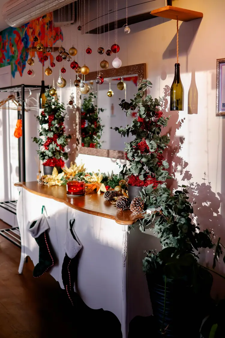 Seven Moves That Turn the Dining Table Into Christmas 6 A white dresser dressed for Christmas with a small tree, greenery, pinecones and stockings