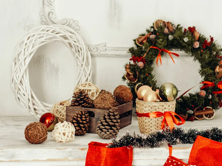 A white shelf styled with a wreath, pinecones and baubles for Christmas