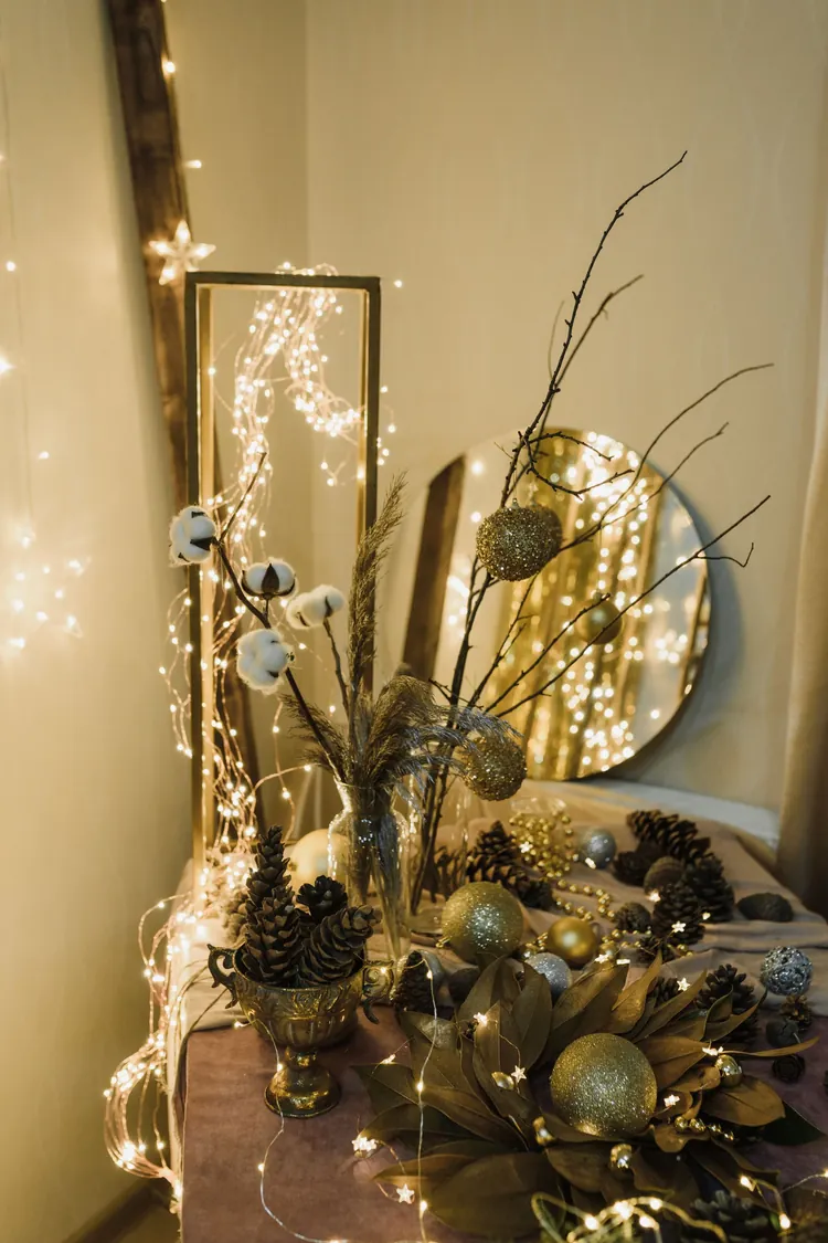 A round mirror reflecting warm fairy lights above a styled Christmas surface