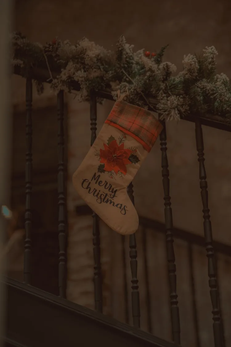 A Christmas stocking hanging on a banister railing with frosted garland