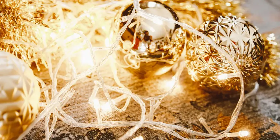 A Warm, Workable Holiday Kitchen: Greenery, Brass and Room to Cook 3 Gold Christmas baubles and warm string lights with gold garland for a kitchen island centerpiece.