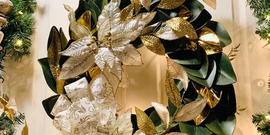A Warm, Workable Holiday Kitchen: Greenery, Brass and Room to Cook 2 Gold and white Christmas wreath with poinsettias and greenery, framed by lit evergreen garland.