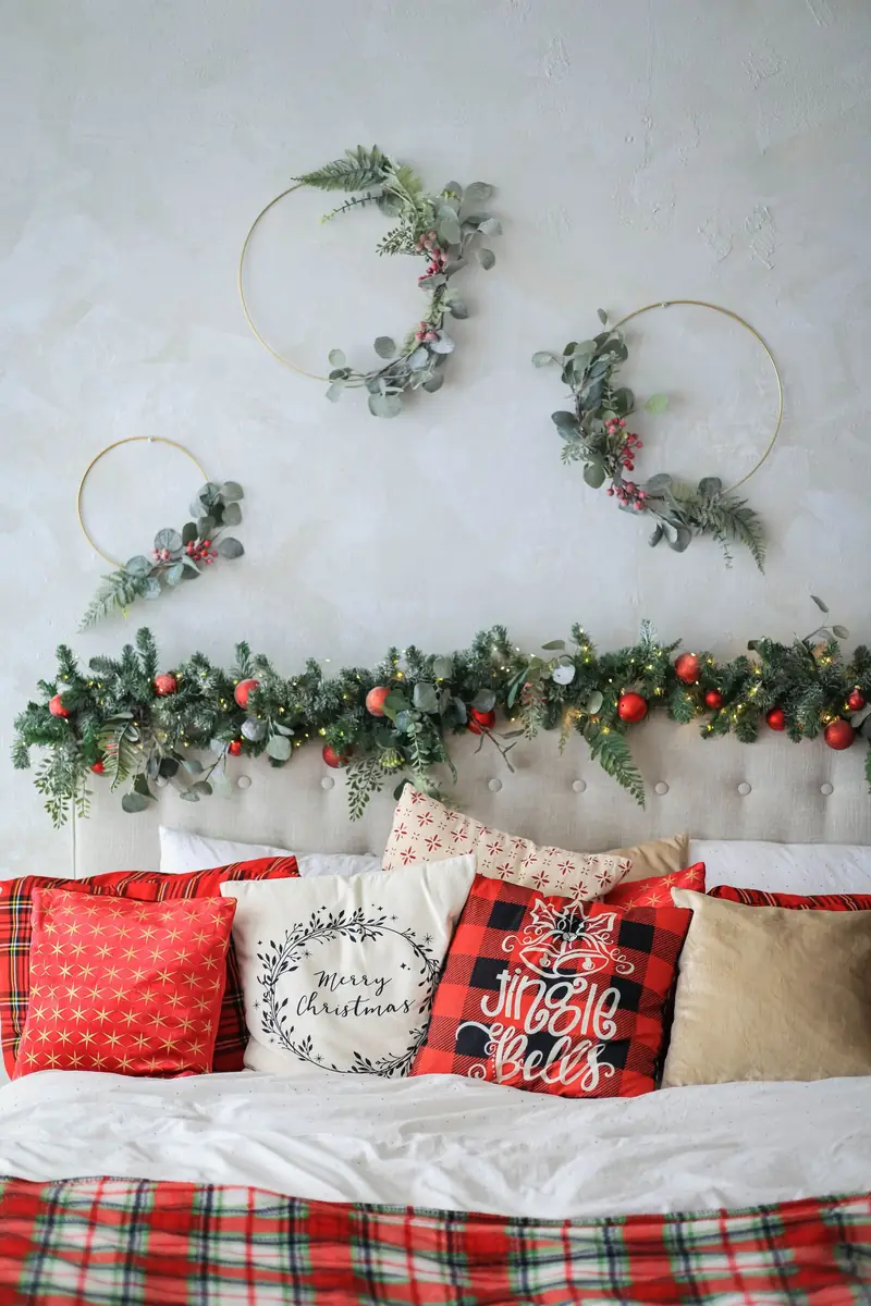 A Calm, Green Holiday Bedroom You Can Actually Sleep In 2 A pine garland with red baubles swagged over a headboard, with gold hoop wreaths dressed in eucalyptus above the bed