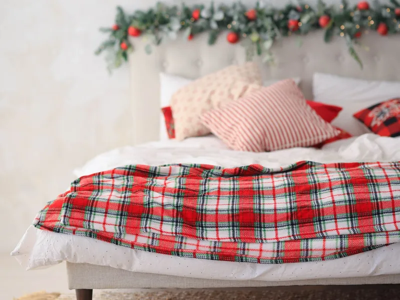 A Calm, Green Holiday Bedroom You Can Actually Sleep In 3 White bedding with a red tartan throw folded across the foot of the bed and festive cushions at the headboard