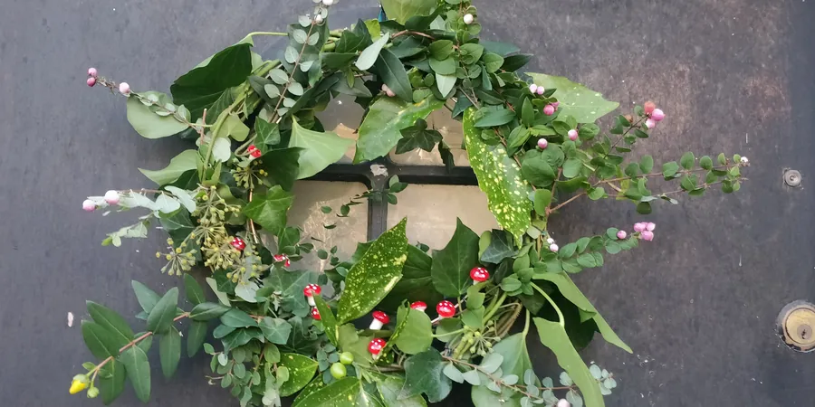 A Warm, Lived In Holiday Room You Can Finish This Weekend 3 A fresh Christmas greenery wreath with ivy, leaves and small pink berries on a dark door.