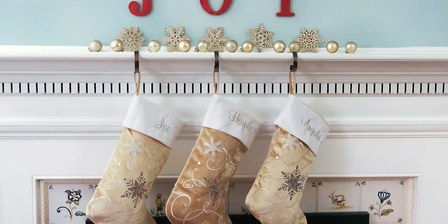 A Warm, Lived In Holiday Room You Can Finish This Weekend 1 A white Christmas mantel with gold ornaments, snowflake decorations and three hanging stockings.