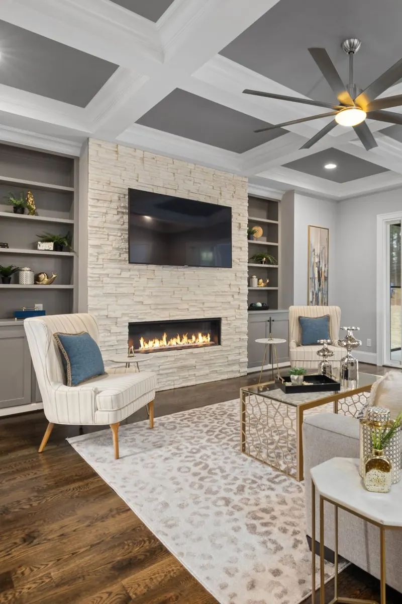 The $37.995M Investment House Its Owner Never Moved Into 2 A living room with a long stone fireplace, built-in shelves, and a coffered ceiling