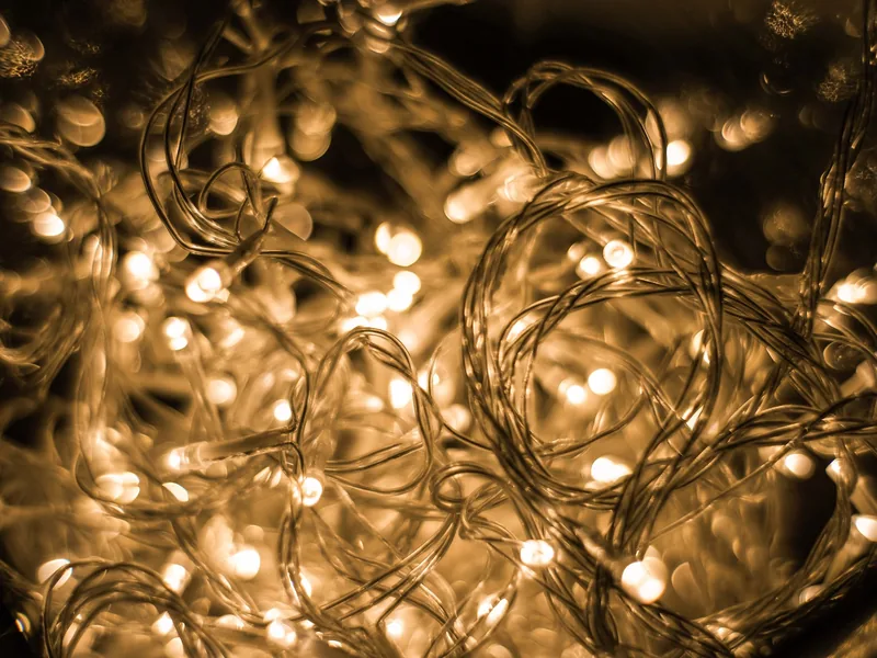 Close-up of warm glowing string lights tangled together against a dark background.