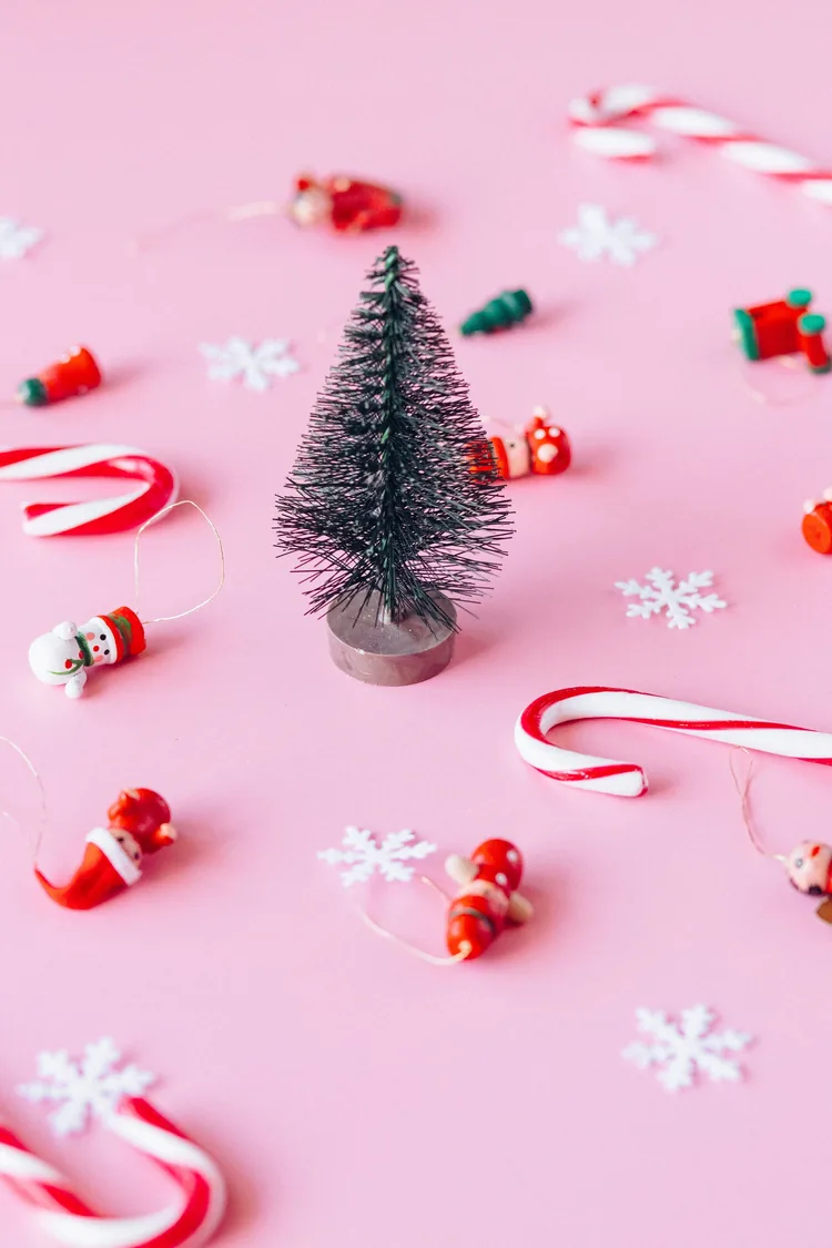 7 Ways to Make Pink Feel Like Christmas, Not a Party 7 A mini Christmas tree on a pink background with candy canes and small ornaments.