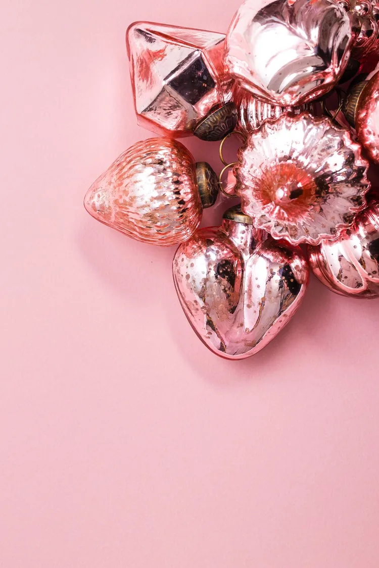 7 Ways to Make Pink Feel Like Christmas, Not a Party 3 Rose gold Christmas ornaments on a pink background.