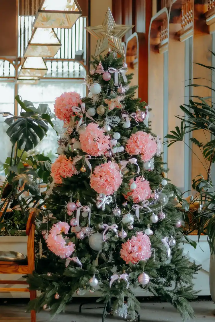 7 Ways to Make Pink Feel Like Christmas, Not a Party 1 A green Christmas tree dressed with pink flowers, pink bows and silver baubles.
